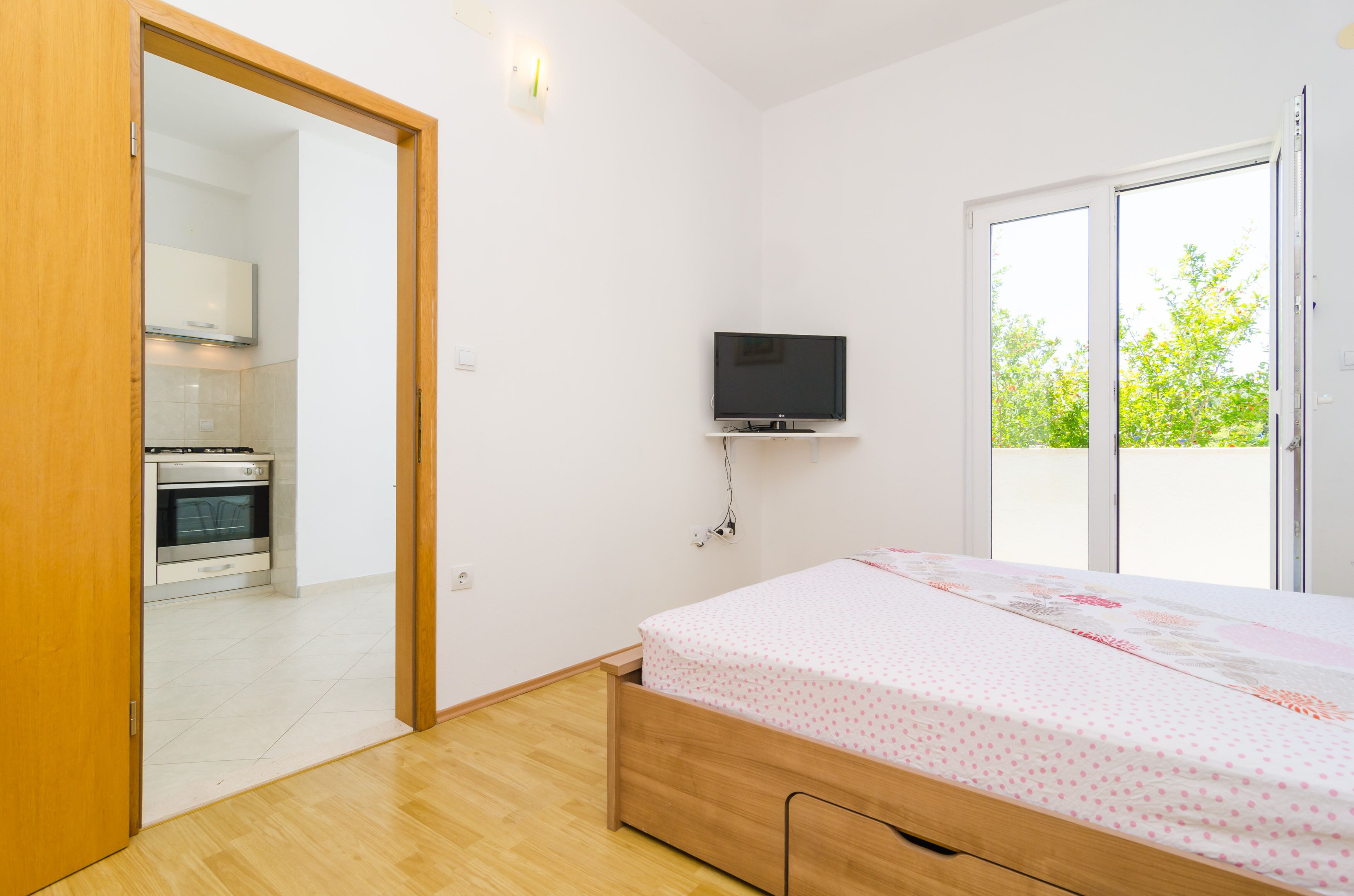 Una camera da letto con un letto, una televisione a muro e vista sull'esterno tramite una porta scorrevole.