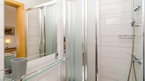 Ein modernes Badezimmer mit Duschkabine aus Glas, einer Glastrennwand und einer sichtbaren Dusche.
