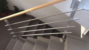 Eine moderne Treppe mit Holzhandlauf und Metallspindeln.