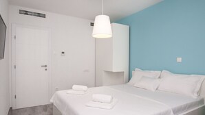 Une chambre d’hôtel moderne avec un grand lit, un lampadaire blanc au plafond et un mur d’accent bleu.