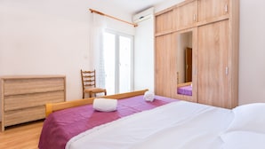 A bedroom with a bed, wooden wardrobe, and a chair. - Magdales - Comfort Three Bedroom Apartment (Omis)