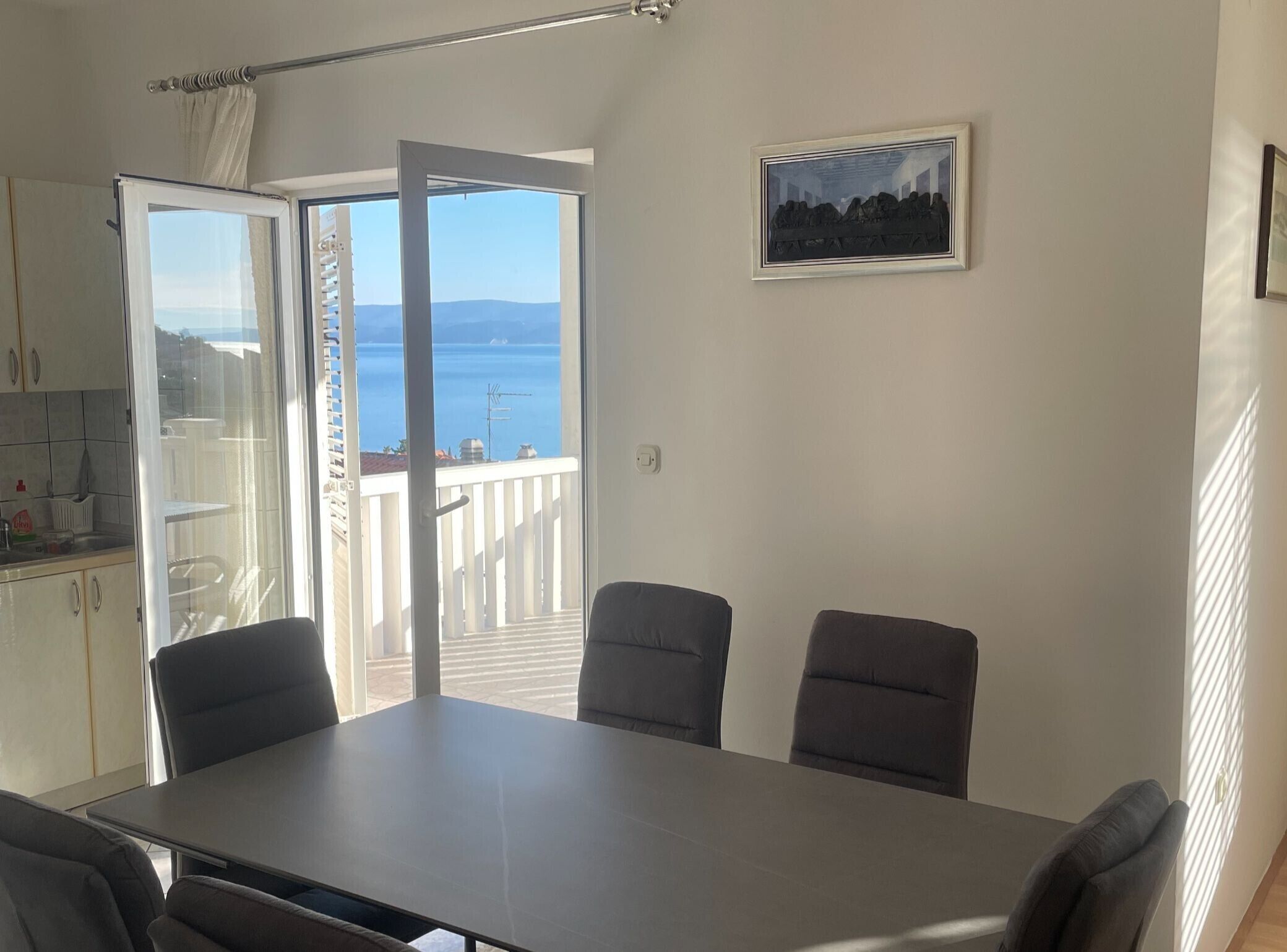 A room with a balcony, a dining table, and chairs.