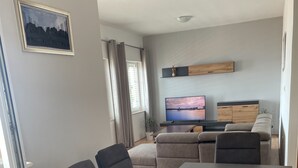 A modern living room with a sofa, TV, and a dining table. - Magdales - Comfort Three Bedroom Apartment (Omis)