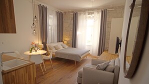 Ett modernt sovrum med en säng, en soffa, ett litet bord med stolar och en tv.