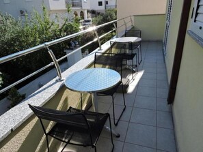 Enjoy a peaceful moment on this balcony with two tables and a chair, offering a serene view.