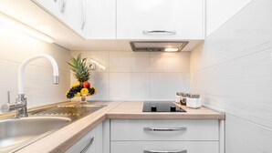 Een moderne keuken met witte kastjes, een roestvrijstalen spoelbak en een fruitschaal op het aanrecht.