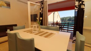 A dining area with a table, chairs, and a view of a balcony with a railing.