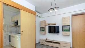 A compact living space with a kitchenette, a flat-screen TV mounted on the wall, and a wooden cabinet. - Apartments Radojković Lumbarda -One Bedroom Apartment with Terrace and Partial Sea View(A1) (Lumbarda)