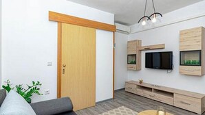 A modern living room with a sofa, a coffee table, a TV mounted on the wall, and built-in wooden cabinets. - Apartments Radojković Lumbarda -One Bedroom Apartment with Terrace and Partial Sea View(A1) (Lumbarda)