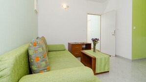 A small, clean room with a green sofa, a wooden desk, and a mirror.