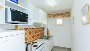 A compact kitchen with white appliances, a microwave, a stove, and a sink. - Villa Bind Twin Room with Patio and Garden View R1 (Obod)