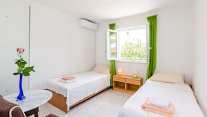 A small, clean room with two single beds, a small table, and a window with curtains. - Villa Bind Twin Room with Patio and Garden View R1 (Obod)