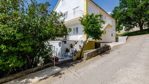 A two-story building with a white facade, a yellow accent wall, and a staircase leading to the upper floor. - Villa Bind Twin Room with Patio and Garden View R1 (Obod)