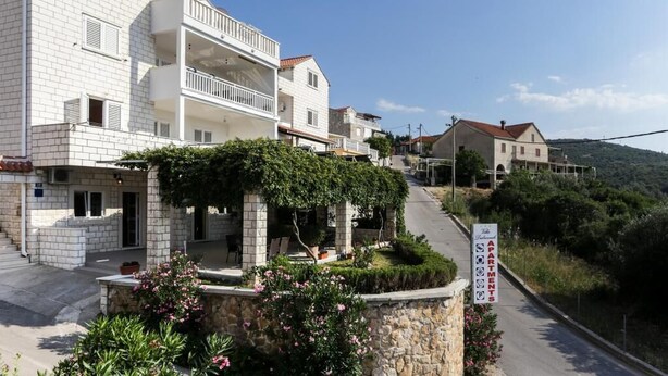 Un edificio de varios pisos con balcones, un sendero de piedra y un letrero que indica que es un complejo de apartamentos.
