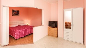 Un dormitorio con cama, televisor, armario y un mueble pequeño.