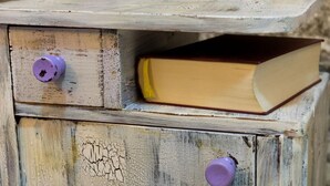Un cofre de fusta rústic amb dues pomes morades i un llibre a l'interior.