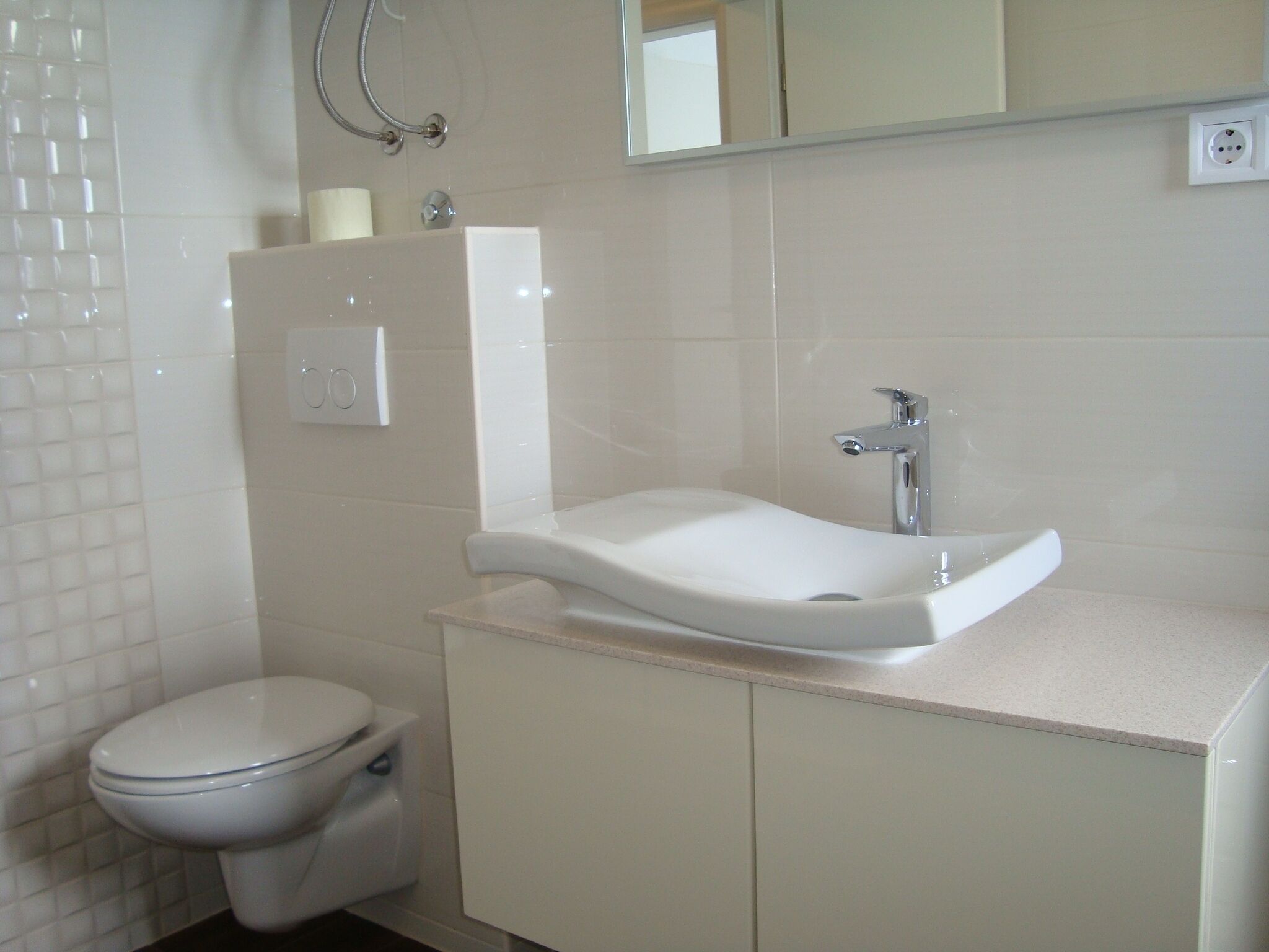 A bathroom with a white toilet, a sink with a mirror above it, and a shower area.