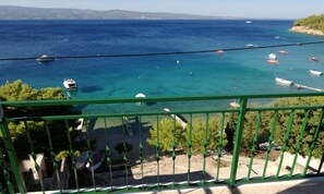 Un balcon avec vue sur la mer, les bateaux et une côte lointaine.