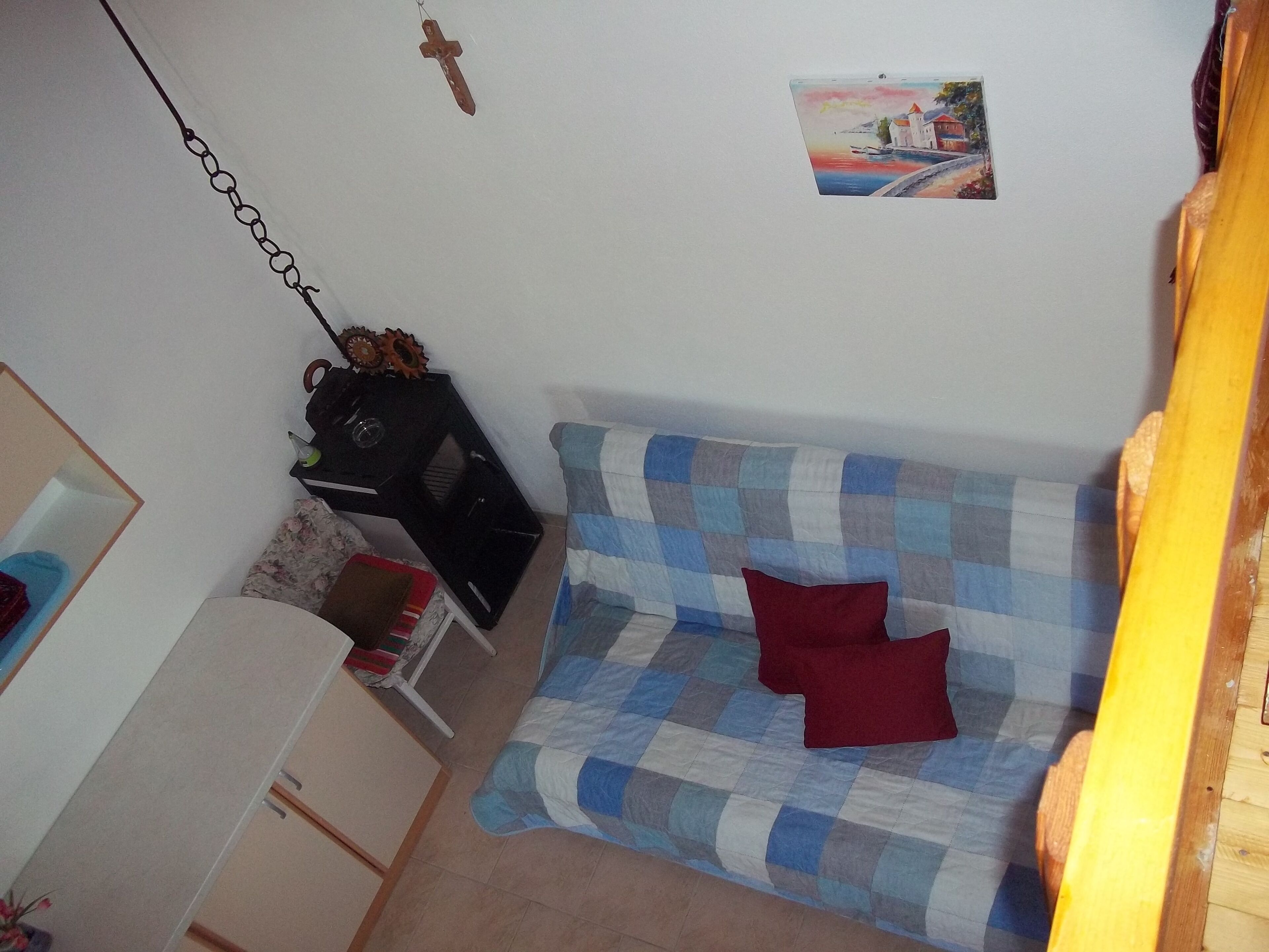 A small, cozy room with a checkered sofa, a wooden sideboard, and a wall-mounted picture.