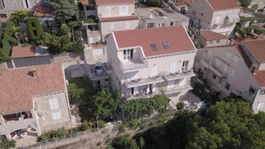 Un immeuble à plusieurs étages, doté d’un toit recouvert de tuiles rouges, de balcons et d’une antenne parabolique.