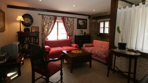 Una sala de estar acogedora con chimenea, un sofá rojo, una mesa de centro de madera y una estantería.