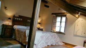 Un dormitorio con dos camas, vigas de madera, una ventana con cortinas y una obra de arte colgada en la pared.