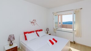 A bedroom with a bed, bedside lamps, a window with a view, and a radiator.
