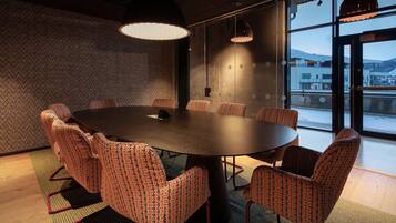 Un salón de conferencias con una mesa redonda, sillas estampadas e iluminación colgante.