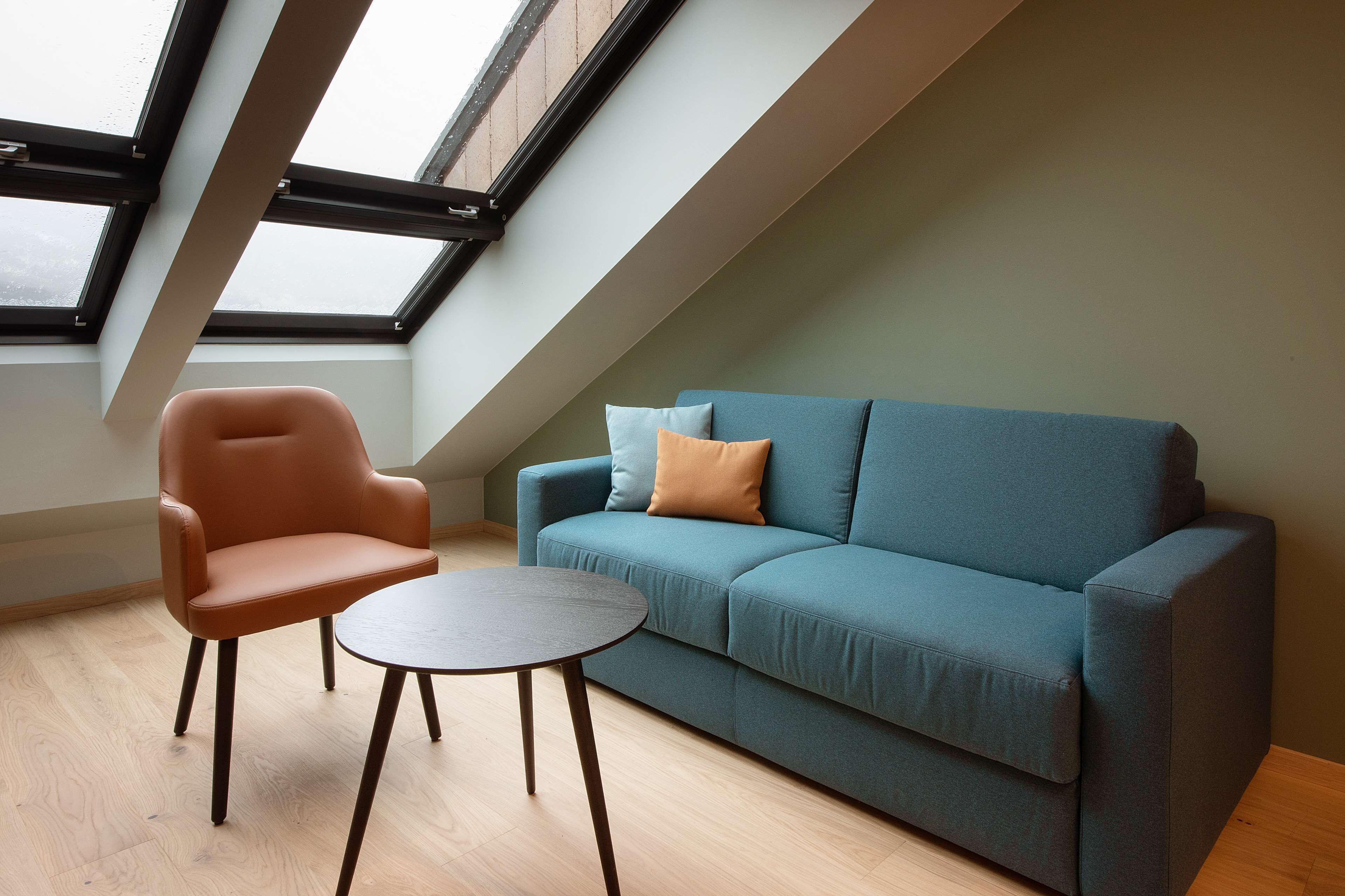 Una habitación moderna con sofá, una silla y una mesita.