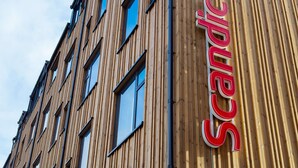 A building with vertical wooden paneling and a prominent red sign with the word "Scandic".
