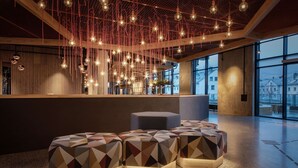 A modern interior with hanging light fixtures, geometric seating, and large windows. - Scandic Voss (Voss)