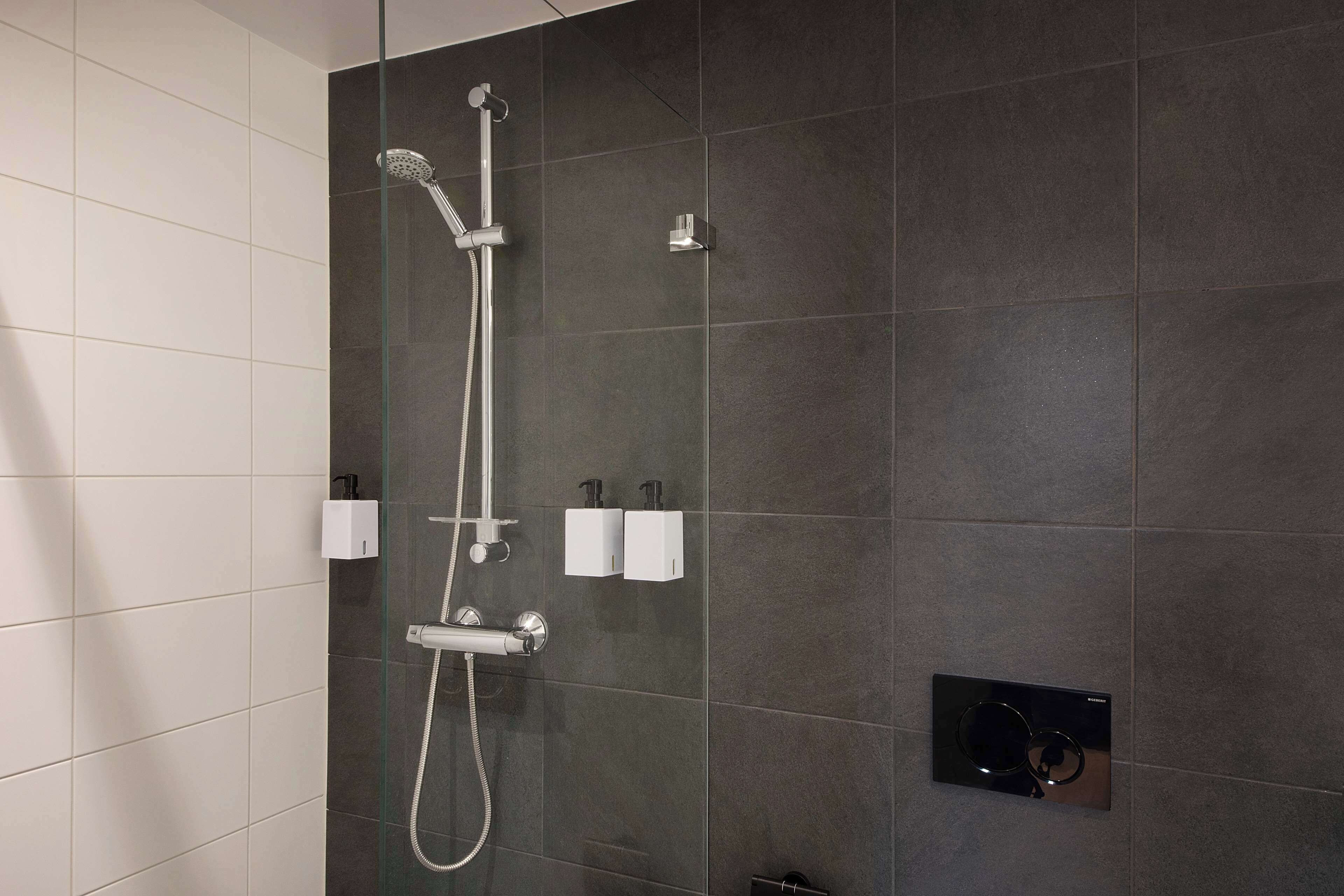Um chuveiro moderno com um chuveiro manual e uma torneira fixada na parede.