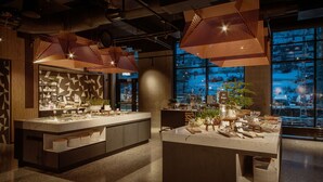 A modern kitchen with a central island, pendant lighting, and a view of the cityscape through large windows. - Scandic Voss (Voss)