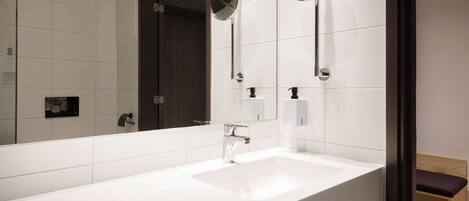 Un baño moderno con un lavabo blanco, dos espejos redondos y un banco de madera.
