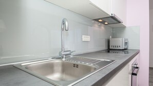 Una cucina moderna con lavello in acciaio inossidabile, forno a microonde e forno integrato.