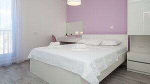 Una camera da letto moderna con un letto grande, un comodino, uno specchio e una finestra con tende leggere.