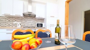 A modern kitchen with white cabinets, a microwave, and a fruit bowl on the table. - Apartments Radojković Lumbarda - Comfort Two Bedroom Apartment with Terrace and Sea View (A2) (Lumbarda)