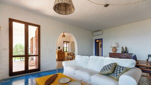 Ein Wohnzimmer mit einem weißen Sofa, einem gelben Tisch mit Tellern und einem blau gefliesten Boden.