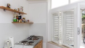 A kitchen with a sink, stove, and shelves above the counter.