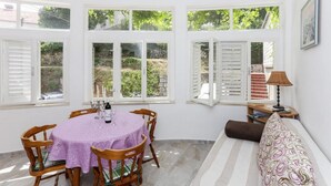 A dining area with a round table covered in a purple tablecloth, surrounded by wooden chairs.