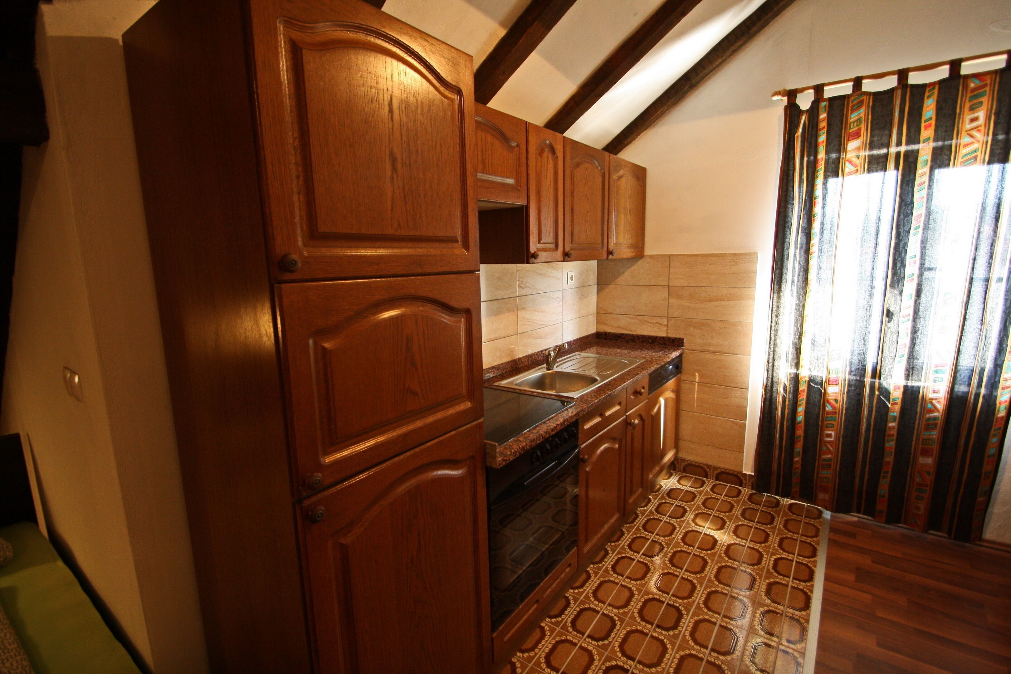 Una cocina con armarios de madera, un fregadero y un suelo estampado.