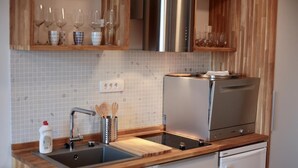 A modern kitchen with a stainless steel refrigerator, a built-in oven, a sink with a wooden countertop, and a wine rack above the sink. - Apartments Cava Dubrovnik - Premium Studio with Patio and Sea View (Dubrovnik)