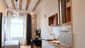 A modern kitchen with wooden beams, a built-in oven, and a dining area with a table and chairs. - Apartments Cava Dubrovnik - Premium Studio with Patio and Sea View (Dubrovnik)
