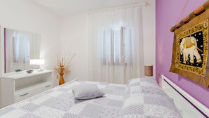Ein Schlafzimmer mit einem Bett, einem Schminktisch mit Spiegel, einem Nachttisch und einem an der Wand hängenden Bild.