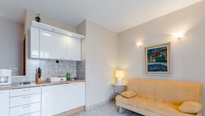 Eine moderne Küche mit weißen Schränken, einer Marmor-Spritzschutzwand und einem gelben Sofa.
