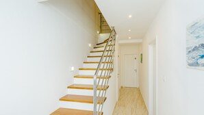 Un escalier moderne avec des marches en bois et des rampes en métal menant à une porte.