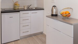 A modern kitchen with white cabinets, a kettle, and a fruit bowl on the counter. - Apartments Pomet - Premium Duplex Studio with City View (Puhiera) (Dubrovnik)