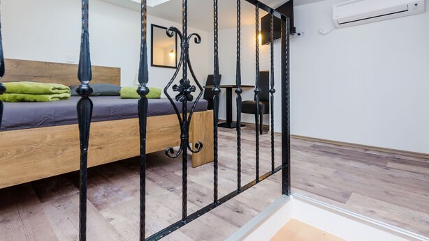 Une chambre à coucher avec un lit en bois, une tête de lit en métal noir, un miroir et un climatiseur fixé au mur.