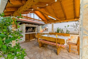 Un patio al aire libre con una mesa y bancos de madera, piso de piedra y pared de piedra.