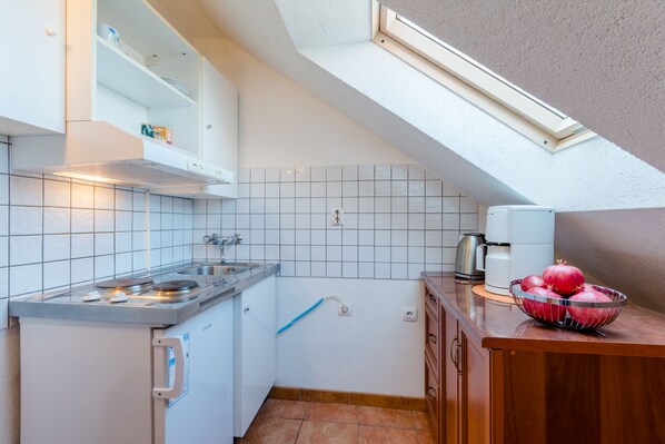 Una cocina compacta con estufa integrada, un lavamanos y una ventana sobre la encimera.